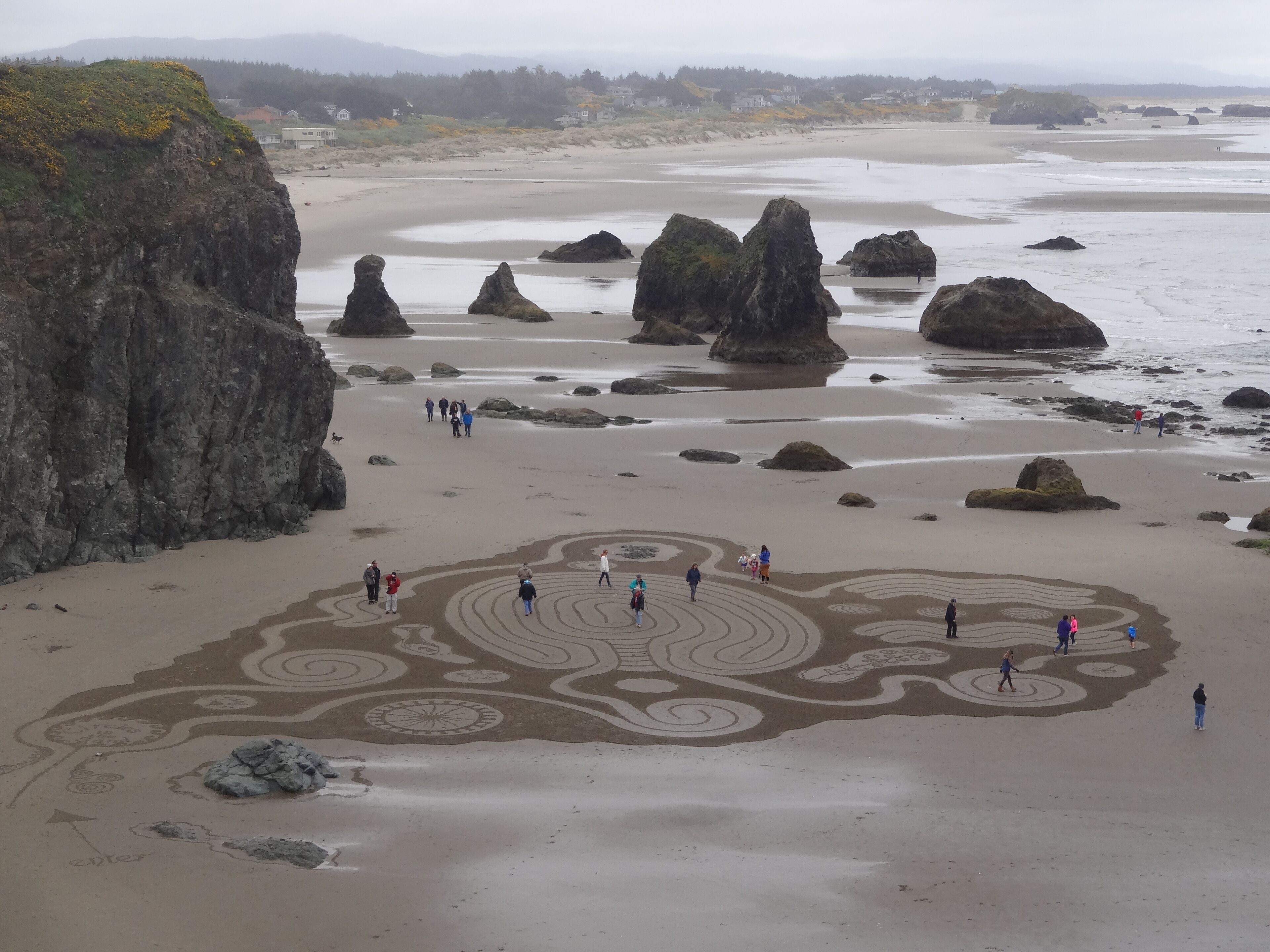A beach with large rocks and a sandy area with circular patterns.