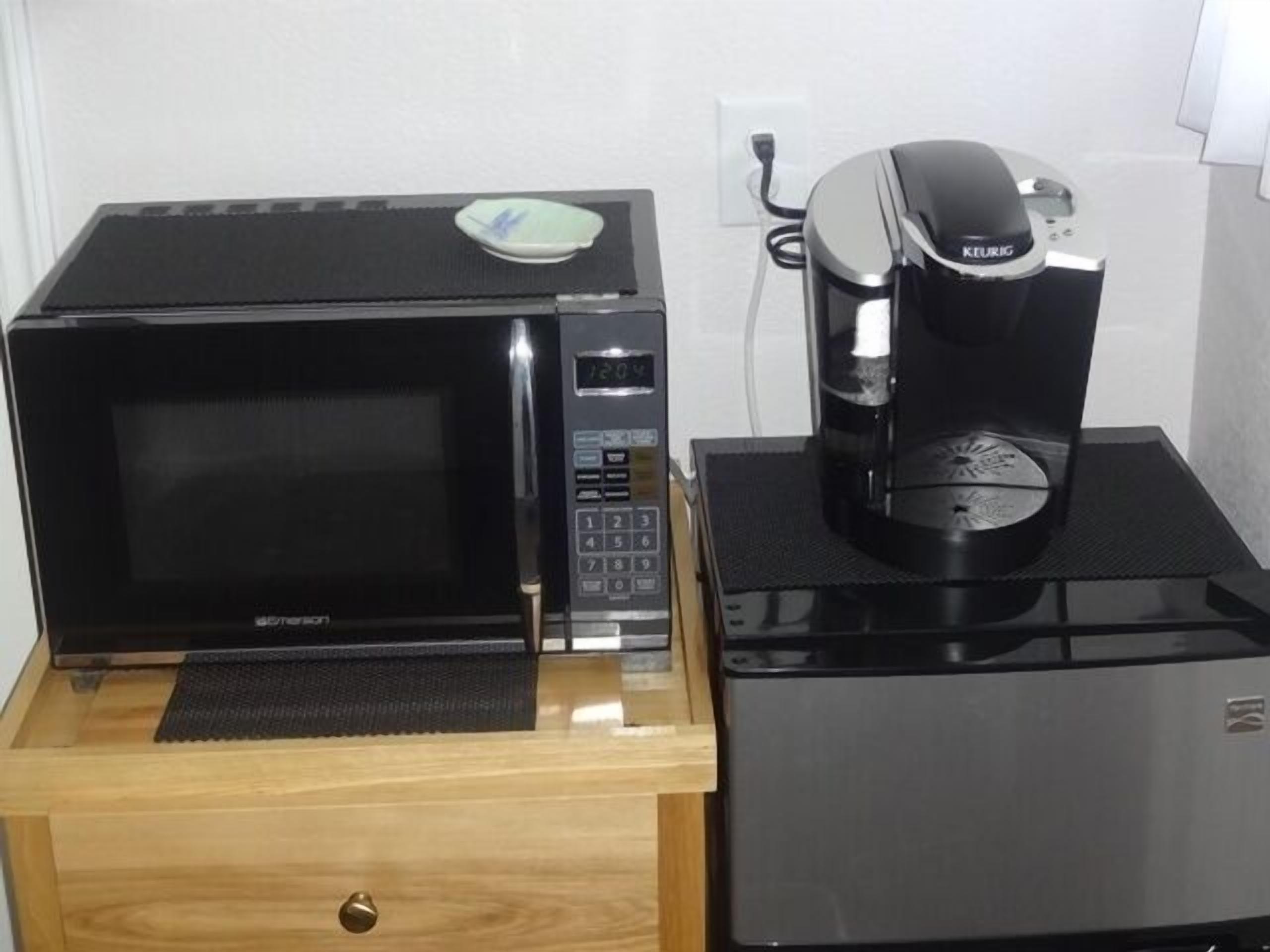 Eine Mikrowelle und eine Kaffeemaschine auf einem Holzkabinett.