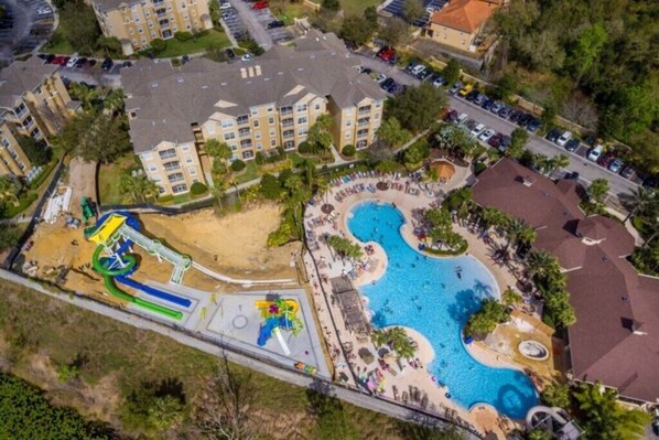 An aerial view of a resort with a large swimming pool, a water park, and multiple apartment buildings. - ALLDISNEY4YOU - RENOVATED VACATION CONDO FAMILY-FRIENDLY (Kissimmee)