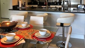 Una cocina moderna con armarios blancos, un refrigerador de acero inoxidable y una isla central con asientos.