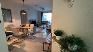 Una sala de estar moderna con comedor, televisor y un amplio ventanal.