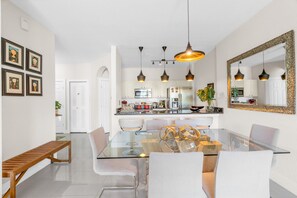 A modern kitchen with white cabinets, stainless steel appliances, and pendant lighting.