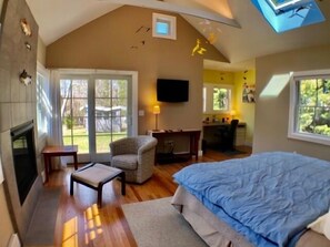 A bedroom with a large bed, a chair, a desk, and a fireplace. - Quiet Neighborhood .2 miles to Skaket Beach (1193) (Orleans)