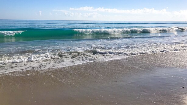 Une plage avec des vagues et un ciel dégagé.