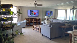 Ein Wohnzimmer mit einer Couch, einem Couchtisch, einem Fernseher und einem Deckenventilator.