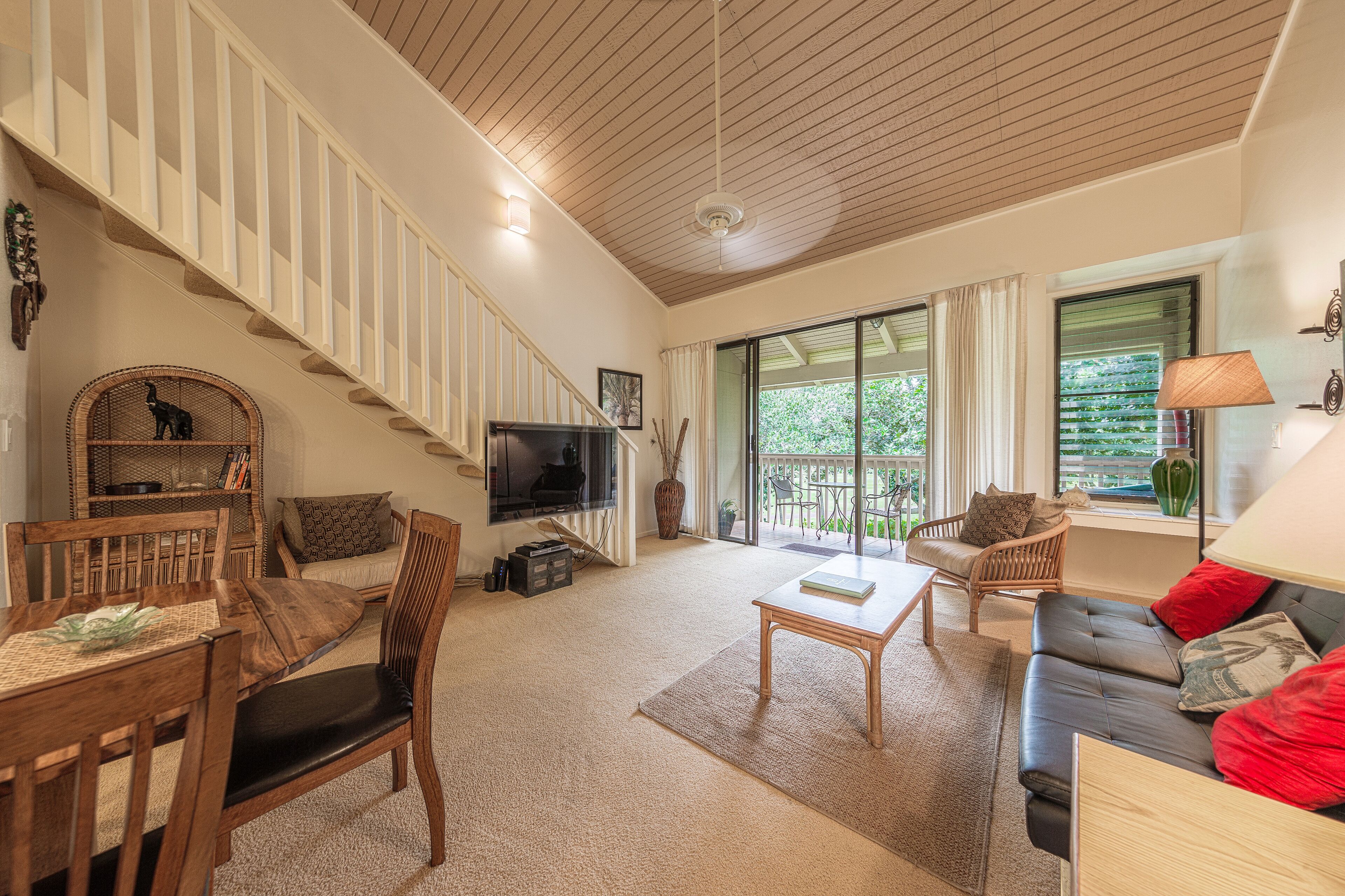 A spacious living area with a staircase, a television, a sofa, and a dining table. - Turtle Bay Luxury 2 Bedroom. Upper Floor with Upgrades.   90/TVU-0512 (Kahuku)