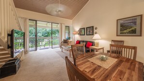 A spacious living area with a wooden dining table, comfortable seating, and a balcony with a view of greenery. - Turtle Bay Luxury 2 Bedroom. Upper Floor with Upgrades.   90/TVU-0512 (Kahuku)