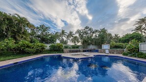 A clear blue swimming pool surrounded by tropical vegetation and a stone wall. - Turtle Bay Luxury 2 Bedroom. Upper Floor with Upgrades.   90/TVU-0512 (Kahuku)