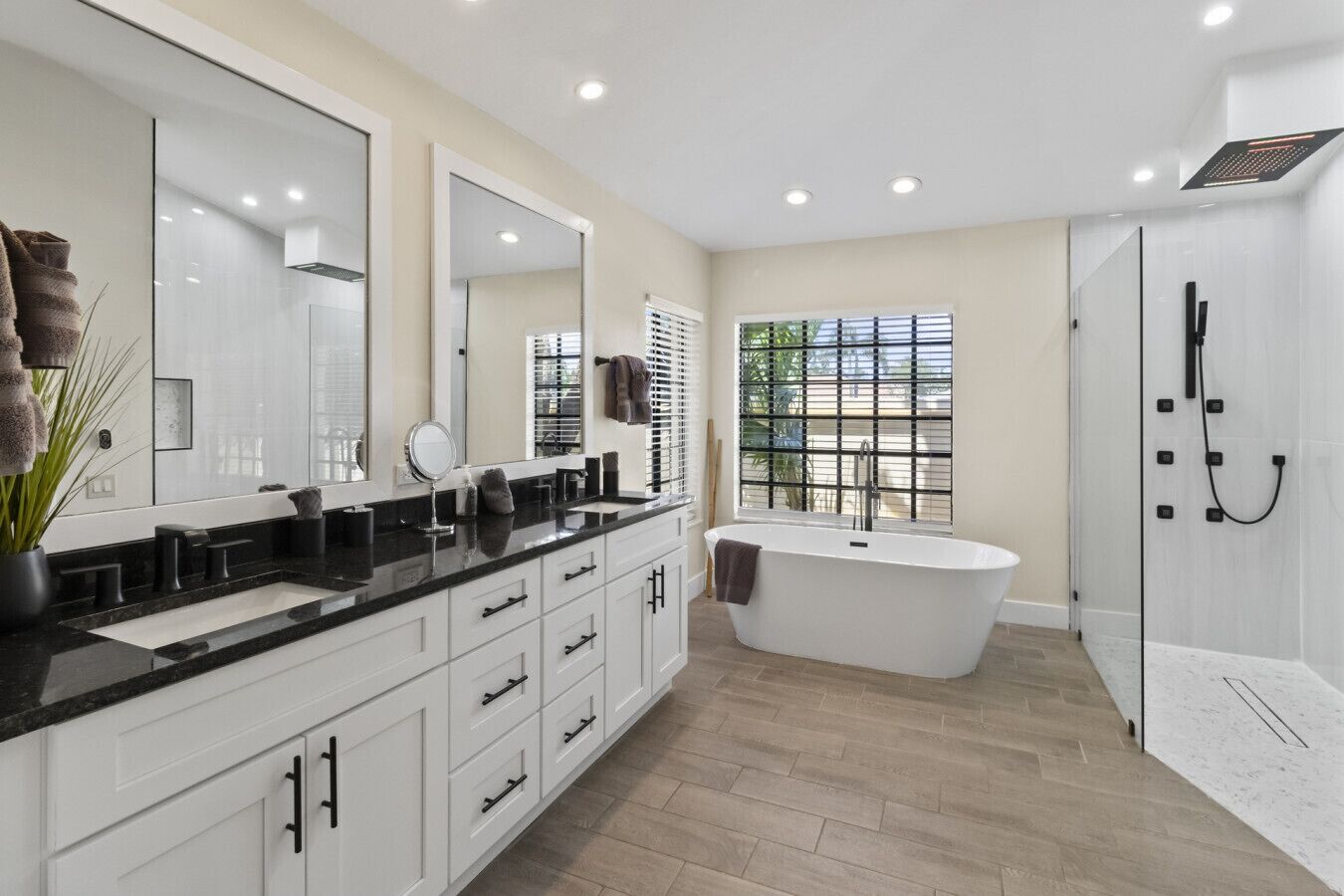 A modern bathroom with a freestanding bathtub, a large mirror, and a shower area.