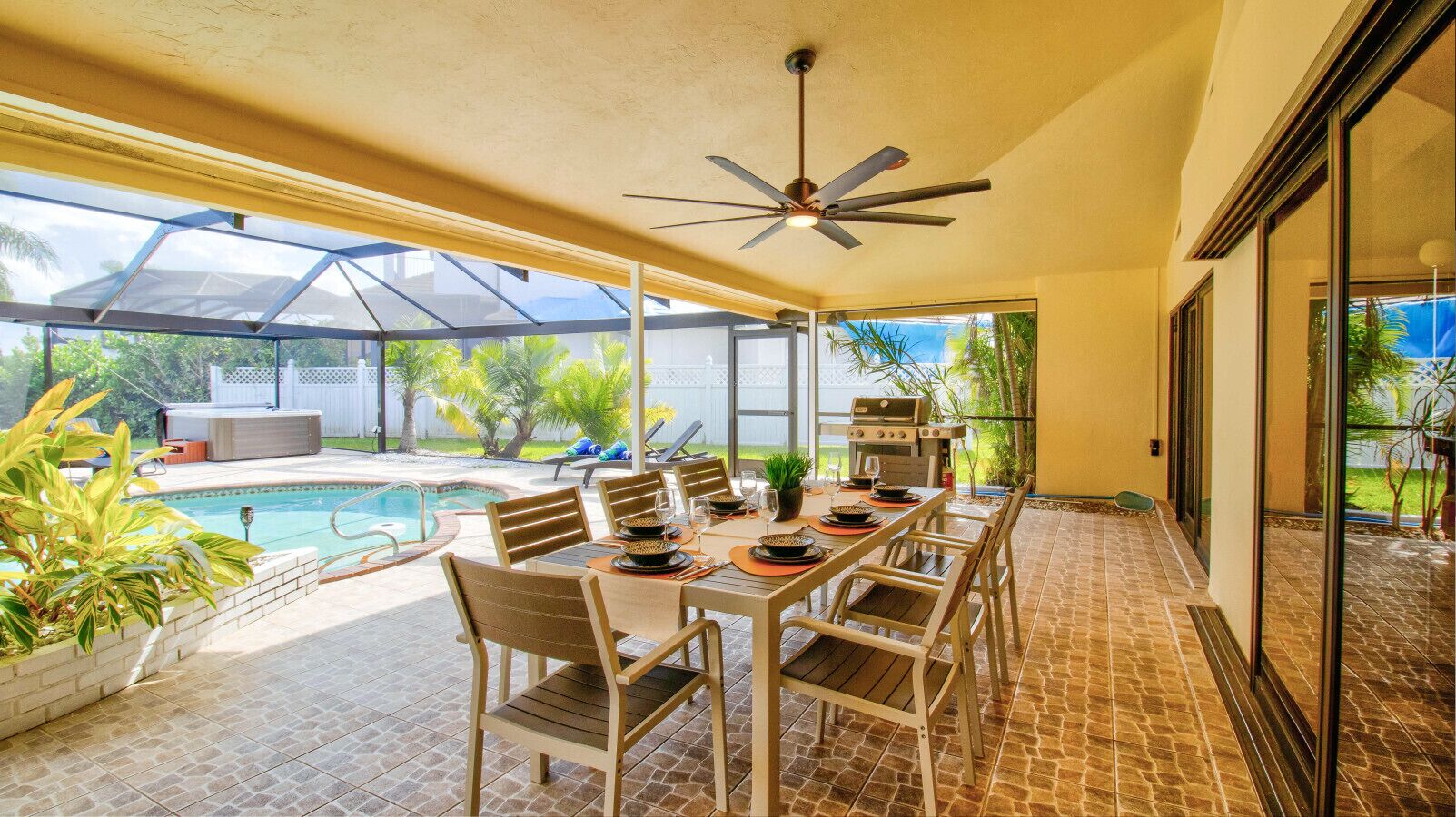 Une terrasse extérieure avec une table à manger, des chaises et un ventilateur de plafond.