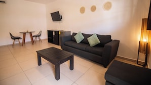 A living room with a sofa, two chairs, a coffee table, a TV, and a lamp.