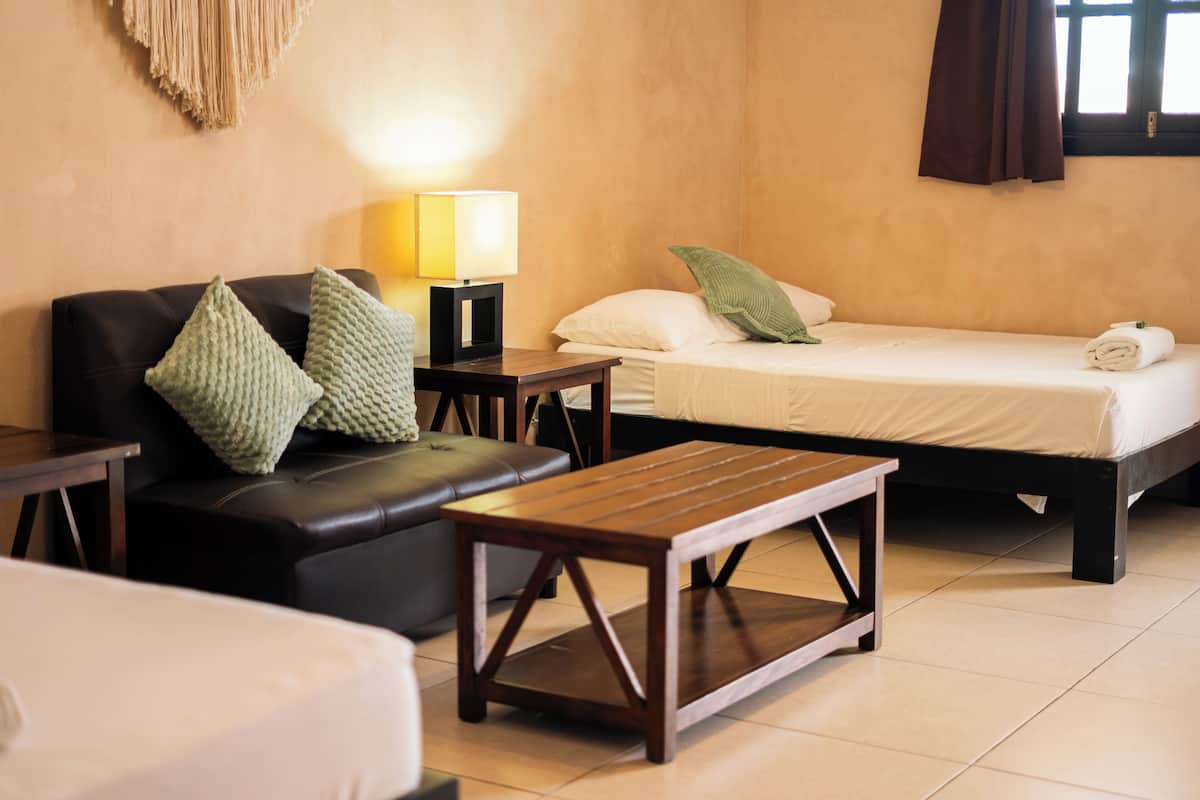 Ein Hotelzimmer mit Bett, einer Couch, einem Holztisch und einer Lampe.