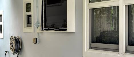 A room with a window, a hose reel, and a wall-mounted electrical outlet.