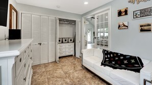 A room with a white closet, a white sofa, and a black throw blanket. - Beach House East of A1A, Private Hot Tub, Outdoor Oasis (Boynton Beach)