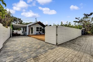 Un vaste espace extérieur aménagé en patio, doté d’un coin salon abrité et d’un petit bâtiment sur lequel est apposée une enseigne.