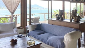 A cozy room with a wooden ceiling, a sofa, a coffee table, and a view of the sea. - The most beautiful view in Ilhabela (IlhaBela)
