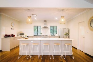 A modern kitchen with a central island, bar stools, and pendant lighting. - Blue Wren—Chic & Spacious Country Pool House (Margaret River)