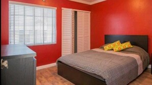 Ein Schlafzimmer mit einem Bett, einem Schminktisch und zwei Fenstern mit Fensterläden.