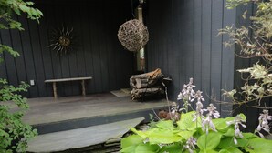 A wooden deck with a bench and a decorative hanging ball. - Peaceful Retreat in White Mountains (Sugar Hill)