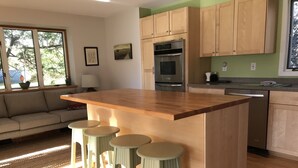 A kitchen with a wooden island, bar stools, a built-in oven, and a dishwasher. - Peaceful Retreat in White Mountains (Sugar Hill)