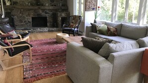 A living room with a stone fireplace, a sofa, a chair, and a rug. - Peaceful Retreat in White Mountains (Sugar Hill)