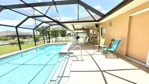 Une piscine extérieure couverte offrant une vue sur une maison et une cour clôturée.