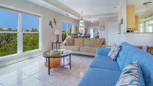 A spacious living room with a blue sofa, a coffee table, and a view of the outdoors.