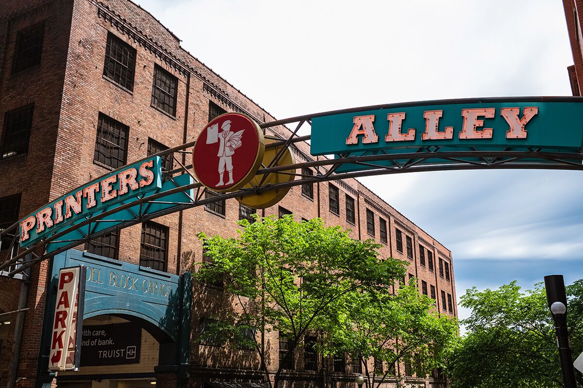 A street sign for Alley with a sign for Printers nearby.