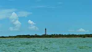 Ein Leuchtturm in einer Küstenlandschaft bei blauem Himmel.