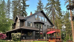 A large, dark wooden house with a balcony and a red umbrella.