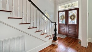 A staircase with white balusters and dark handrails, leading to a door with a wreath. - Heated Pool Access | 5*Clean | Flex Cancelation (Savannah)