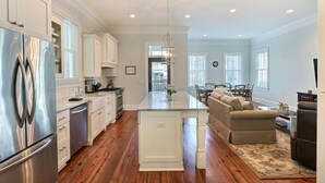 A spacious kitchen with a central island, stainless steel appliances, and a dining area with a sofa and table. - Heated Pool Access | 5*Clean | Flex Cancelation (Savannah)