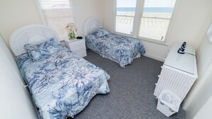 Een slaapkamer met twee bedden, een dressoir en een raam met uitzicht.