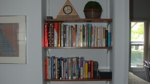 Una estantería con varios libros y un reloj.