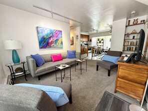 Een moderne woonkamer met een grijze bank, een salontafel en een boekenkast.