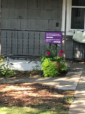 Wegwijzer naar pensions en loft appartementen, een bloembak met bloemen, en een houten hek.