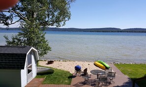 Eine Terrasse mit Grill, Sitzgelegenheiten im Freien und Kajaks am See.