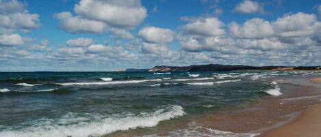 Ein Strand mit Wellen, einem klaren Himmel und Bergen in der Ferne.