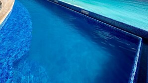 A clear blue pool with a view of the ocean and a distant shoreline. - Gorgeous Caribbean Ocean View (Cancún)