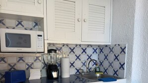 A compact kitchen with white cabinets, a microwave, a blender, and a sink. - Beautiful Ocean View Condo 1 (Cancún)