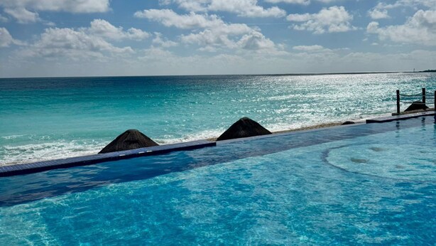 A clear blue pool with a view of the ocean and sky. - Beautiful Ocean View Condo 1 (Cancún)