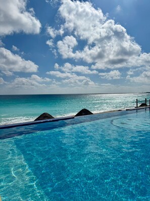 En klar, blå pool med udsigt til hav og himmel.