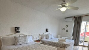 A hotel room with two beds, a ceiling fan, and a view of the outside. - Beautiful Ocean View Condo 1 (Cancún)