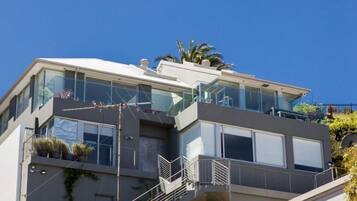 A modern two-story building with large windows, balconies, and a staircase.