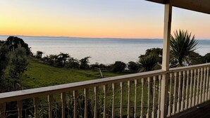 Un balcon avec vue sur la mer et la verdure.