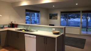 A modern kitchen with a dishwasher, a sink, and a window overlooking a snowy outdoor area. - Moorings - escape (Orford)