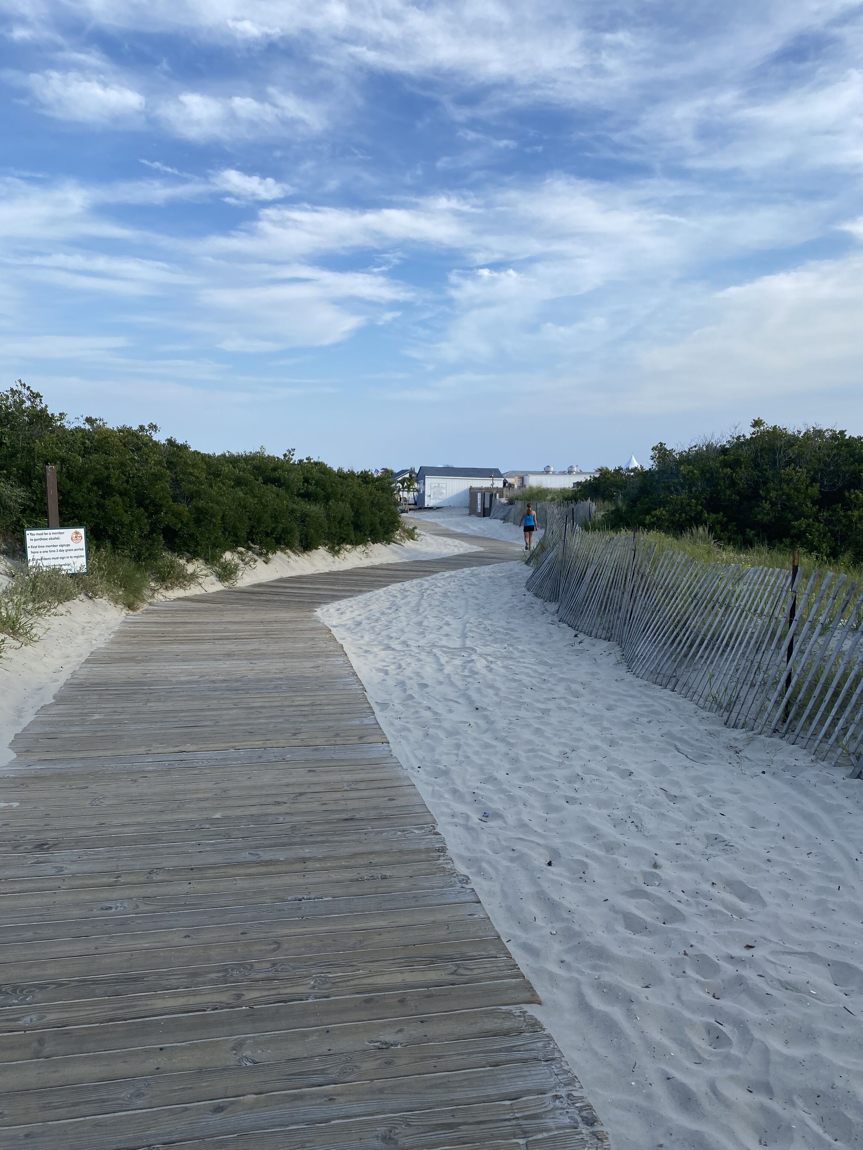 Une promenade en bois mène à une plage de sable, et une clôture en longe un des côtés.