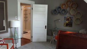 A bedroom with a bed, a desk, a chair, a lamp, and a shower area. - Charming Tree Top Victorian - Two Bedroom Retreat (Boston)