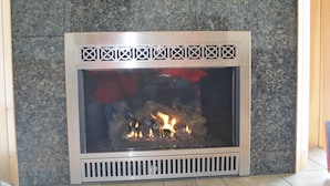 A fireplace with a stone surround and a decorative metal frame. - Elegant, spacious 5 bedroom home on Molasses Pond (Eastbrook)
