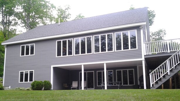A two-story house with a covered porch and a staircase leading to a second floor. - Elegant, spacious 5 bedroom home on Molasses Pond (Eastbrook)
